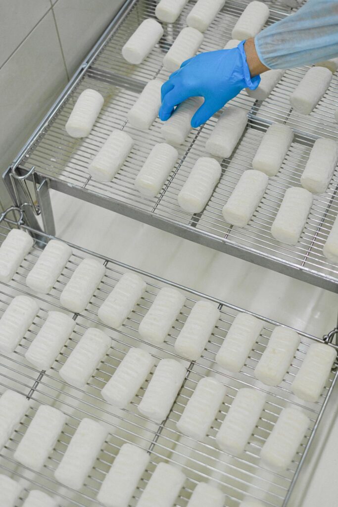 Worker wearing blue glove organizing production line in factory setting.